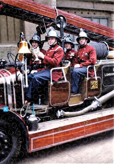 [colorized] A photograph from circa 1930 of Whitechapel fireman holding the trophy they won in the 'Fire Brigades Escape Competition'