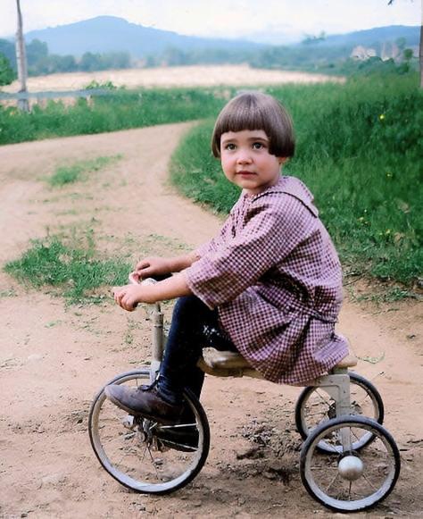 [colorized] A young girl rides her tricycle, 1927