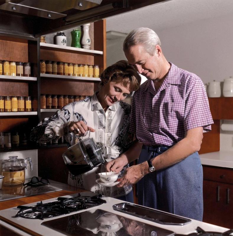 [colorized] Jimmy Stewart holds a cup and saucer while his wife, Gloria, pours him a cup of coffee in the kitchen of their home in California, circa 1965.

Photo by Gene Lester.