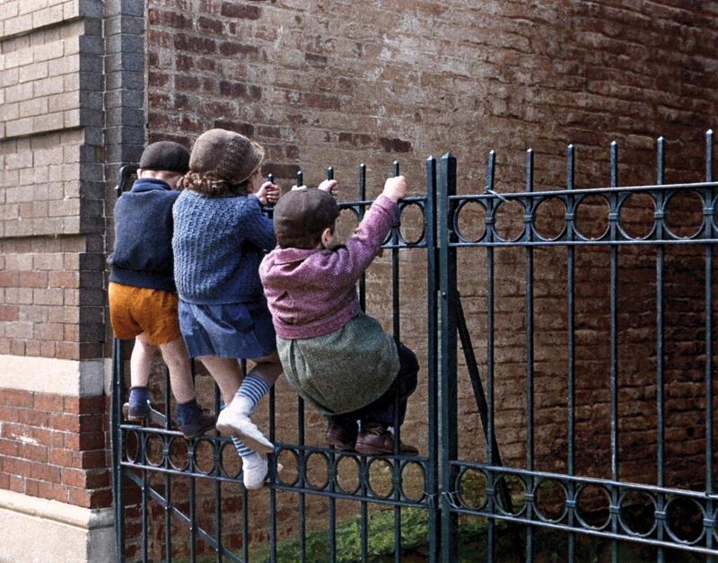 [colorized] Kids playing on a fence, Sutter Avenue, Brownsville, Brooklyn, New York, 1930's - by Joe Schwartz